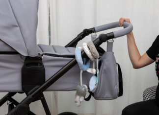 wózek dziecięcy trzymający przez przyszła bądź obecna matkę. Koncept wychowywania i kosztów wychowywania dzieci.